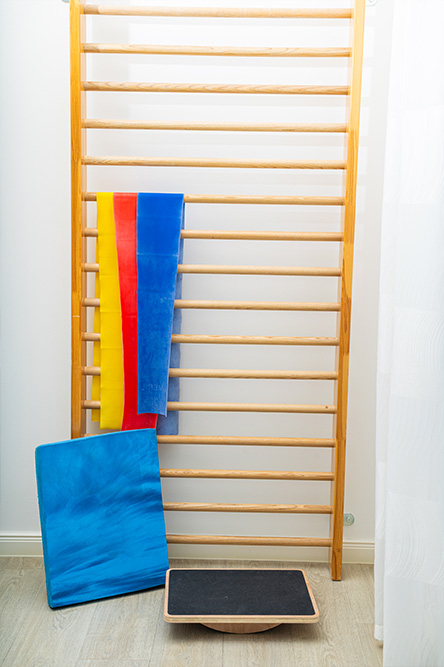 Sprossenwand mit Therapiebändern und Balancebrett